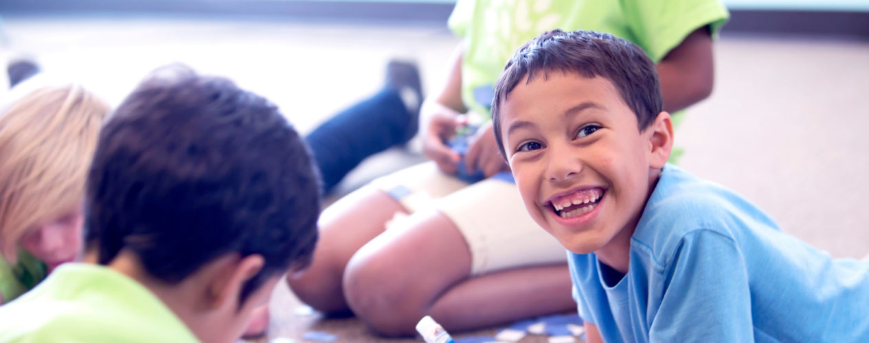 A preteen boy smiles largely as he participates in making his family tree.