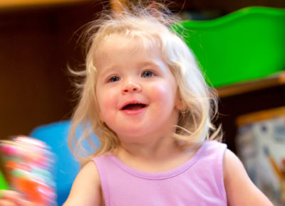 Nursery-aged girl in a lilac top smiles as she plays a simple Valentine's Day game.