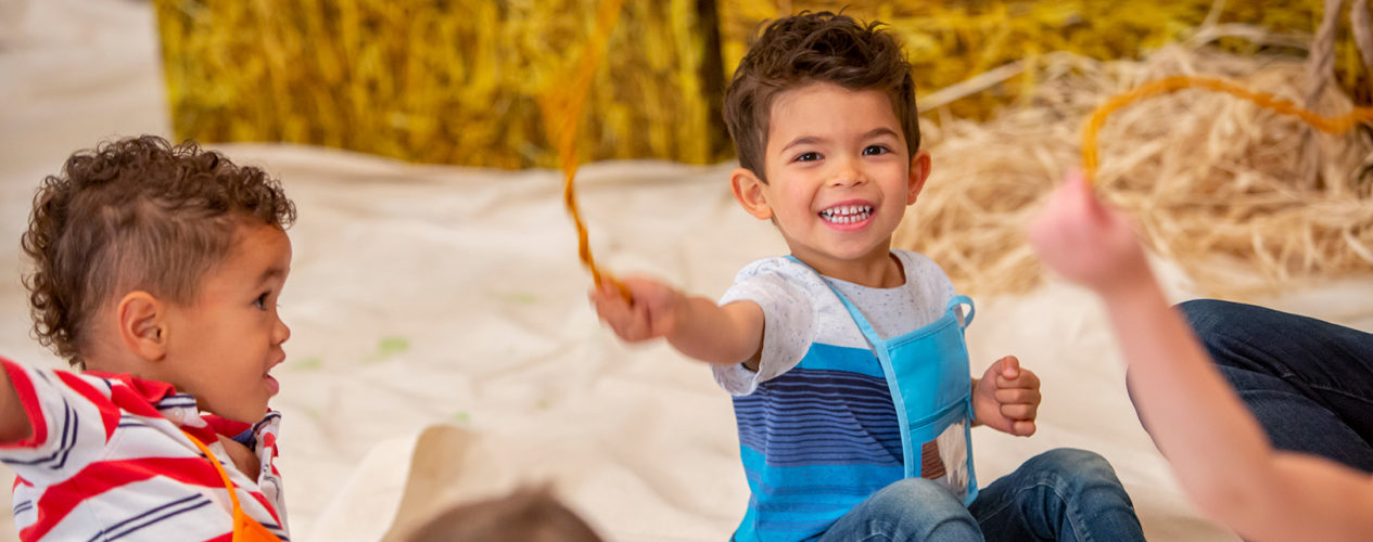 A preschool boy smiles as he participates in a thankful wheel for Thanksgiving.
