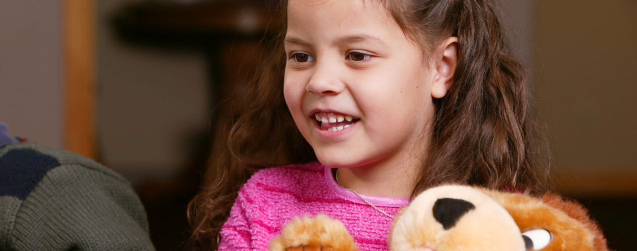 An elementary girl is holding an encouraging prayer bear.