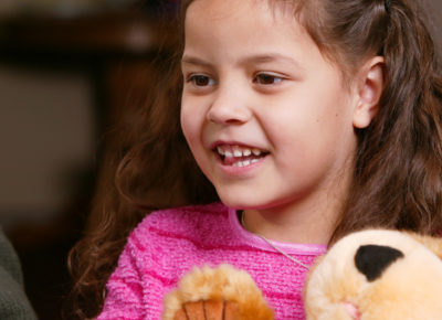 An elementary girl is holding an encouraging prayer bear.