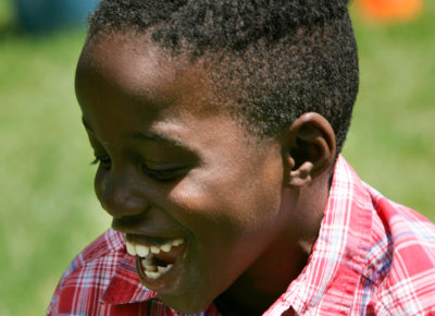 A young boy smiles as he runs around outside.