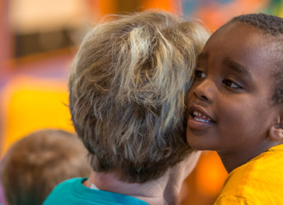 An elementary-aged boy hugging a female volunteer.
