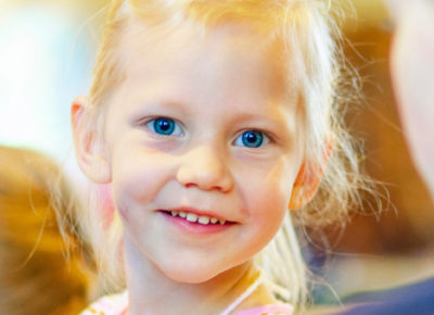 A kindergarten girl smiles at the camera.