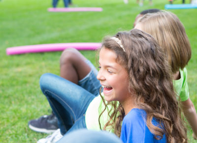 A group of preteens smile as they play a game outside.