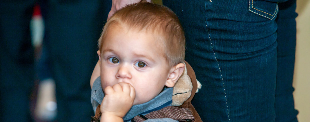 A toddler puts his hand to his mouth during a lesson that uses his senses.
