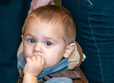 A toddler puts his hand to his mouth during a lesson that uses his senses.