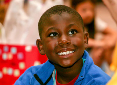 A preteen boy smiles brightly at his small group leader.