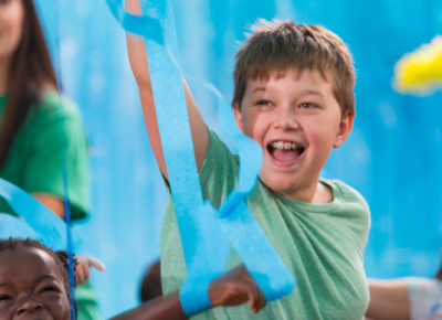 An elementary boy toss blue tissue paper up in the air.