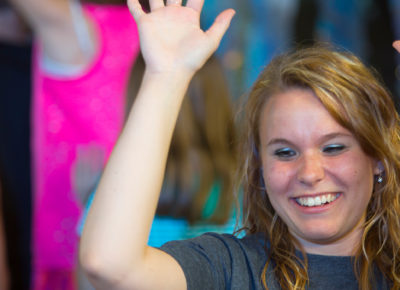 A female volunteer raises her hands in celebration of a child's success.