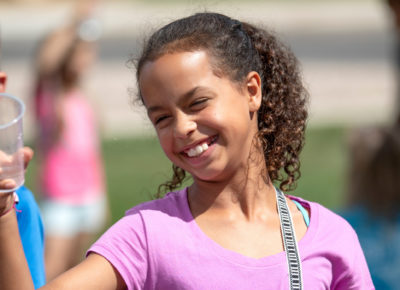 A preteen girl smiles as she plays an outdoor game at VBS.