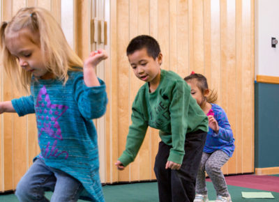 Three first-graders hop from one side of the room to another.
