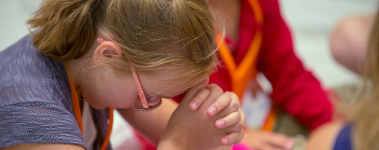 An elementary-aged girl praying.