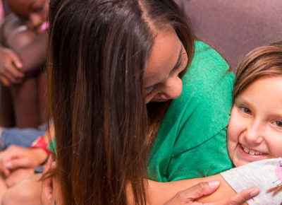 An elementary girl hugs her small group leader during a self-esteem boosting activity.