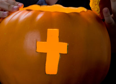 A pumpkin carved with cross in it.