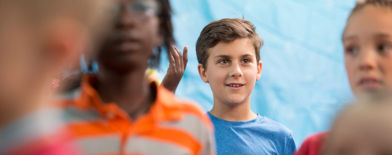 A preteen boy smiles during a large group activity.