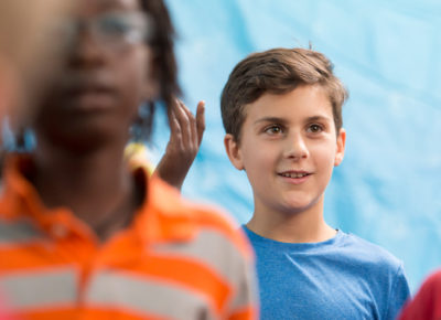 A preteen boy smiles during a large group activity.