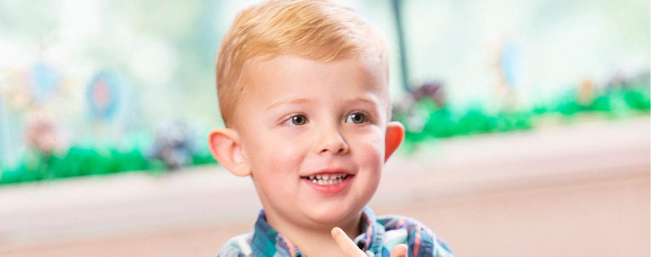 A three-year-old boy smiles in the nursery.