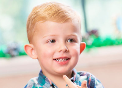 A three-year-old boy smiles in the nursery.