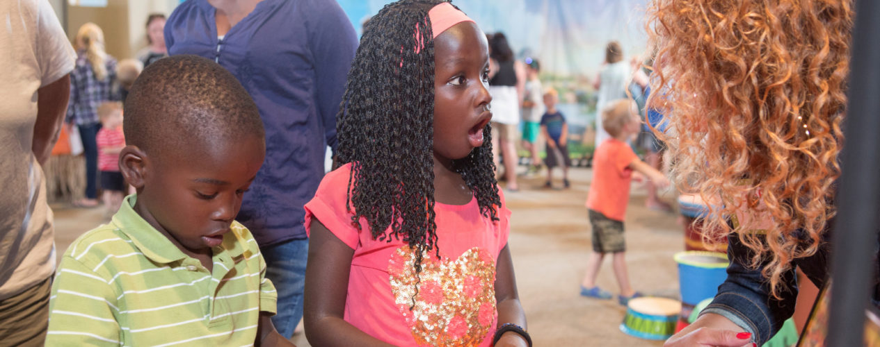 Two elementary aged kids participating in a church's special event. The girl, who is older, looks in awe over the activity.