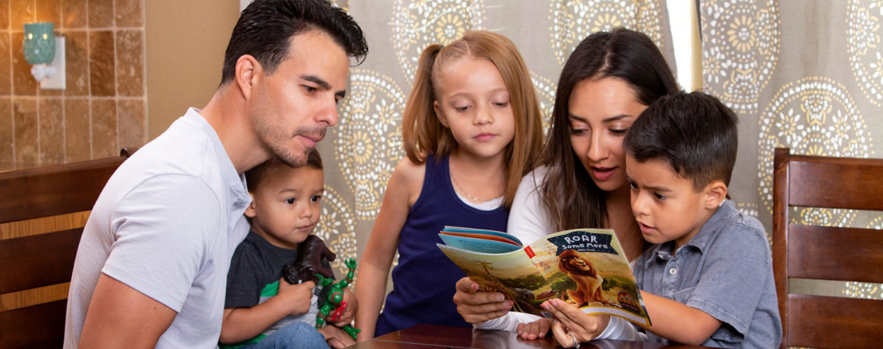 A family with three kids read over a children's devotional together.
