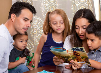 A family with three kids read over a children's devotional together.