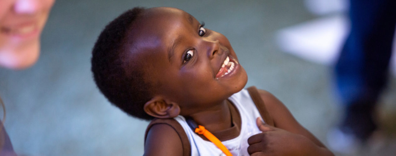 A preschool boy is tilting his head and smiling during the children's message.