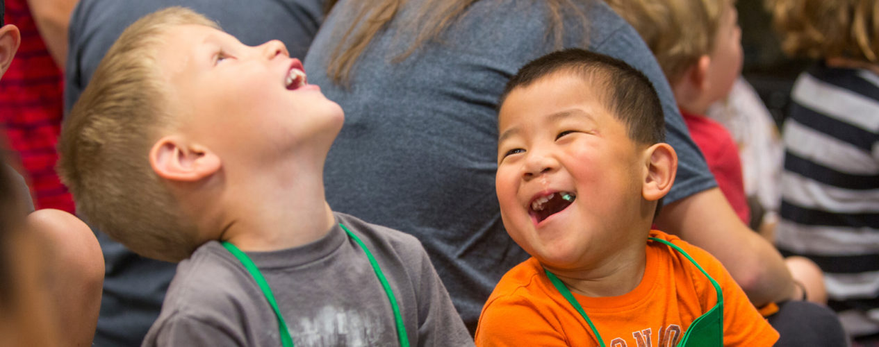 Two preschool boys are laughing during a scripture memorization game.