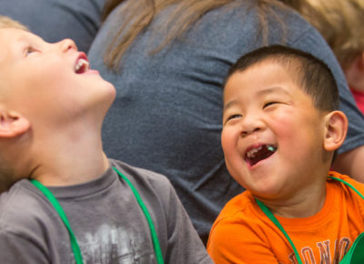 Two preschool boys are laughing during a scripture memorization game.