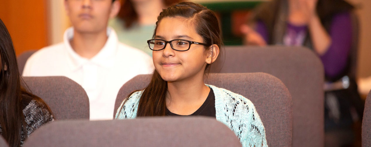 Preteen girl smiling in her church sanctuary as the grateful graffiti project is explained..