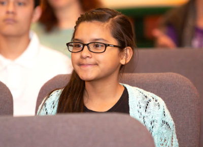 Preteen girl smiling in her church sanctuary as the grateful graffiti project is explained..
