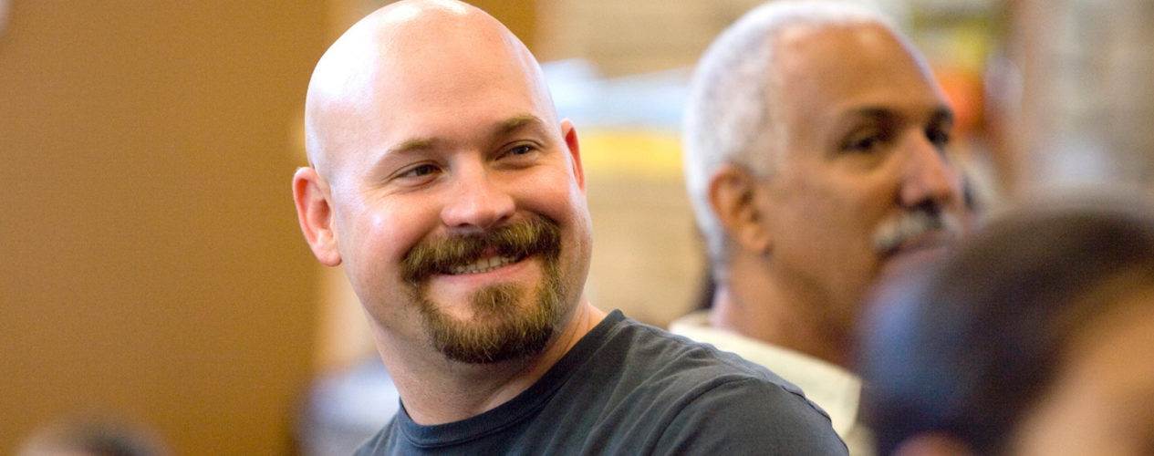 Middle-aged man smiling over his shoulder at church.
