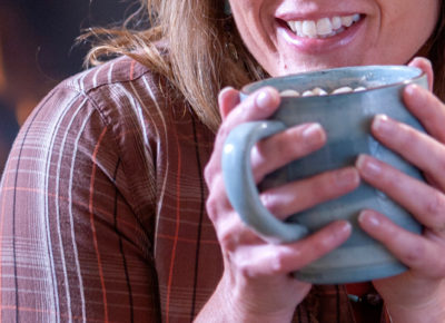 A church visitor holds a mug of hot cocoa with marshmallows up to her mouth.
