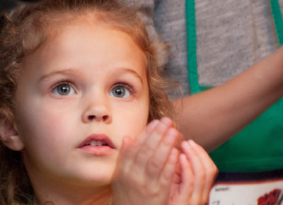 A young elementary girl stares in wonder as she cups her hands.