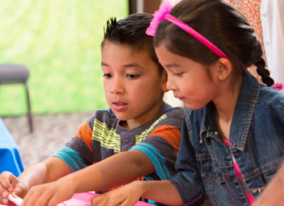 An older elementary-aged brother and sister work on a Easter craft together.