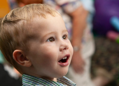 A toddler boy smiles in awe as he enters his classroom.