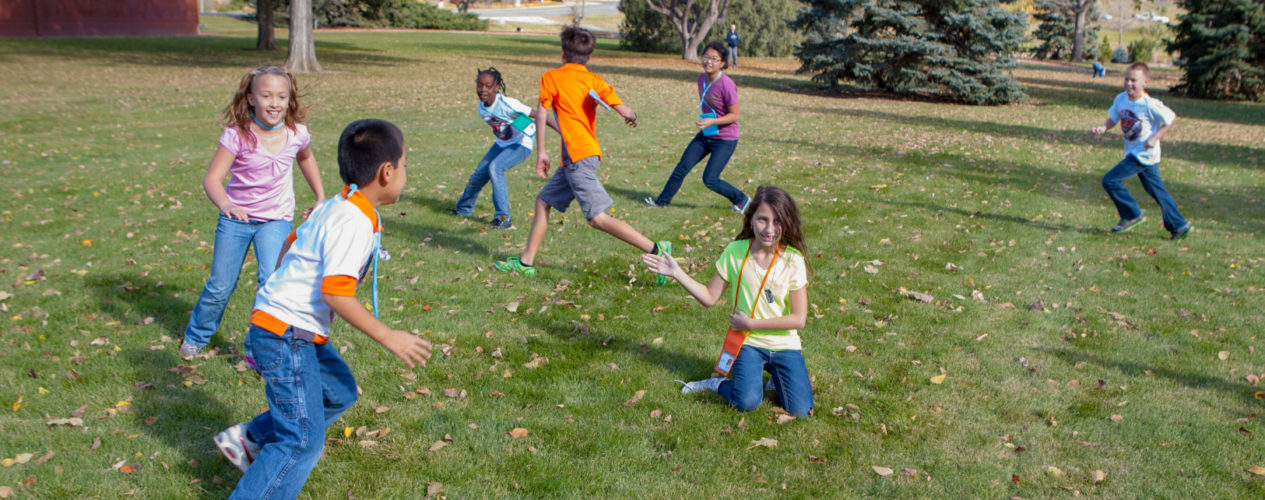 A group of older elementary kids running around outside playing tag.