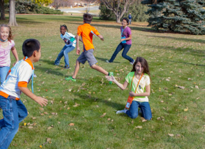 A group of older elementary kids running around outside playing tag.