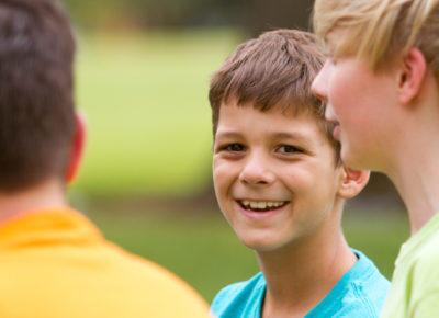 A group of boys smiling outside during a patience game.