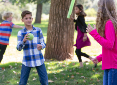 A group of preteens are playing a game at a park during the fall.