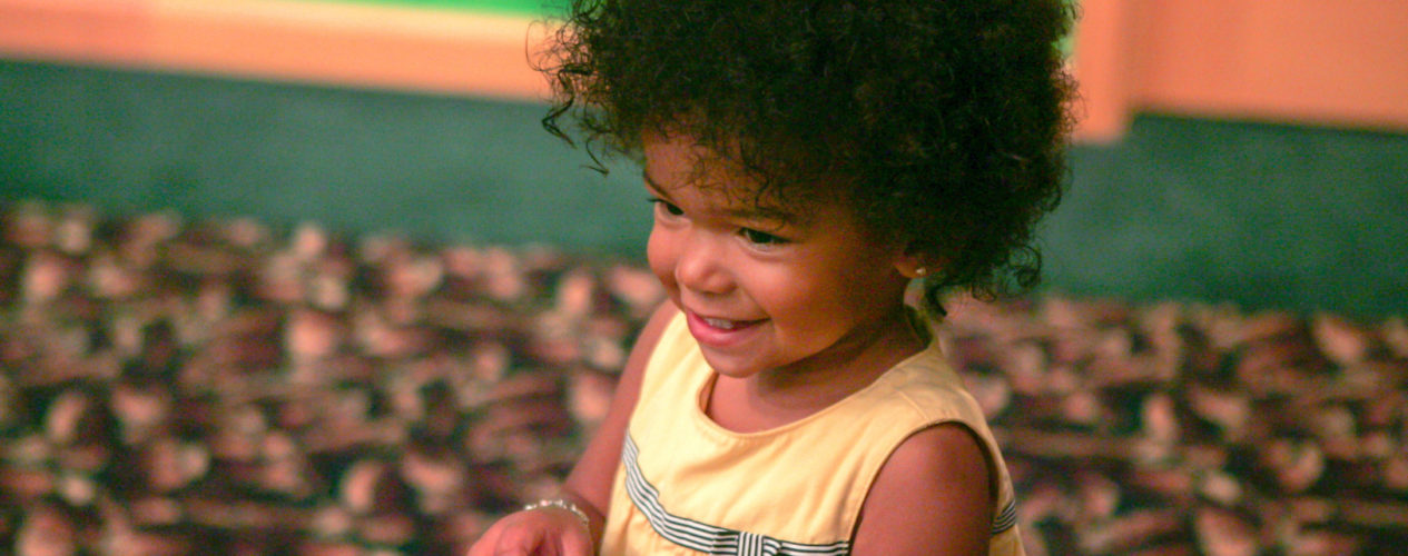 A two year old girl smiles as she sings a song about God's creation.
