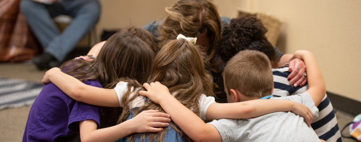 A group of children are huddled in prayer.