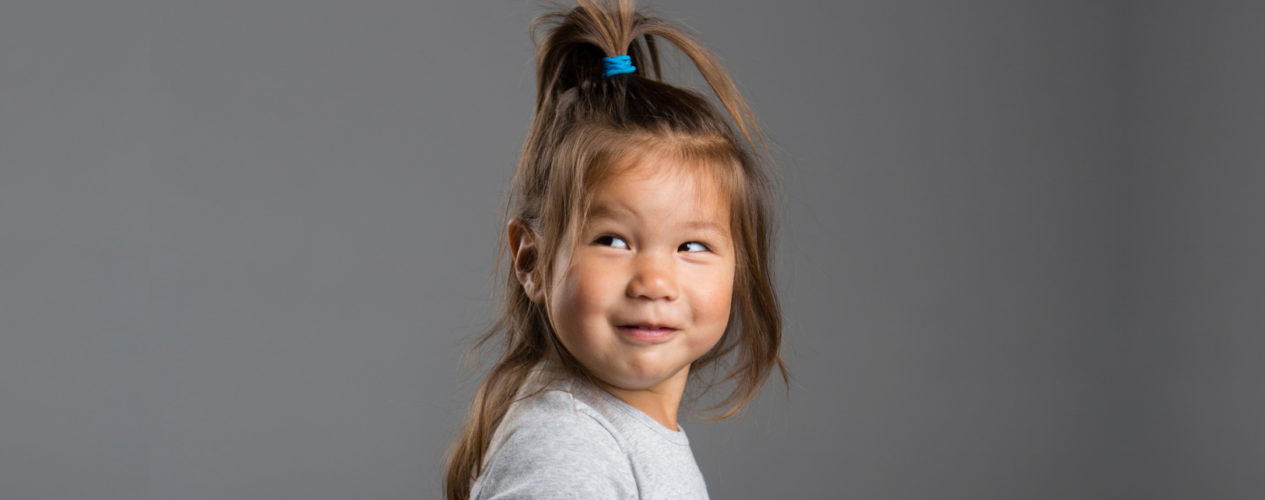 A girl toddler smiles as she looks over her shoulder.