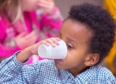 Preschool boy drinks out of a plastic disposable cup during snack time.