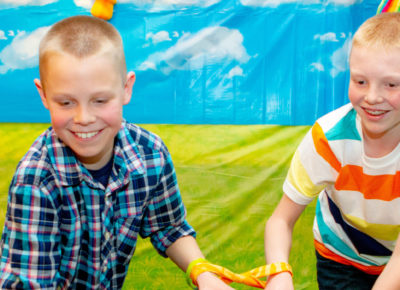 Two preteen boys play a game in a classroom that has brightly colored walls.