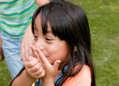 Elementary girl covers her mouth like she just said something she wasn't supposed to.