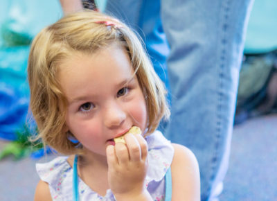 An elementary girl eating a snack.