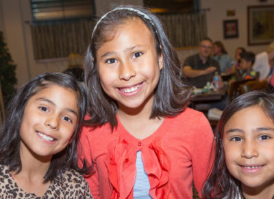 Three girls ranging from early elementary to preteen smile for a photo.