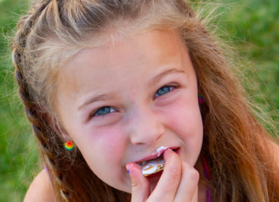 An elementary girl eats locust legs snacks.