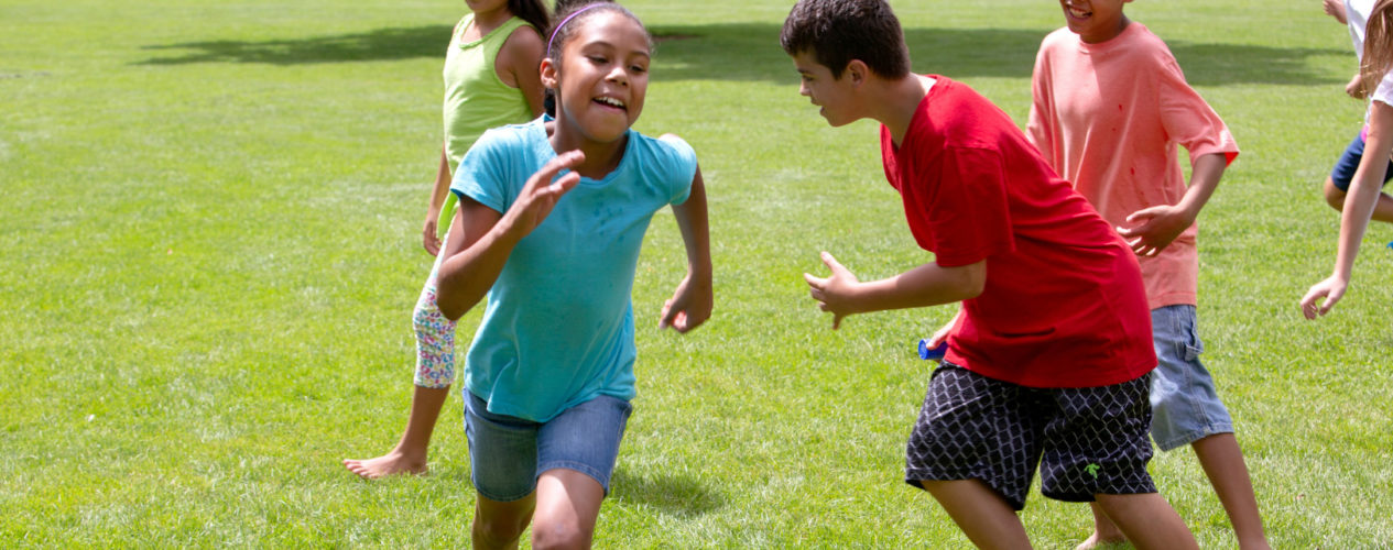 A group of older elementary kids running around outside while playing a game of tag.